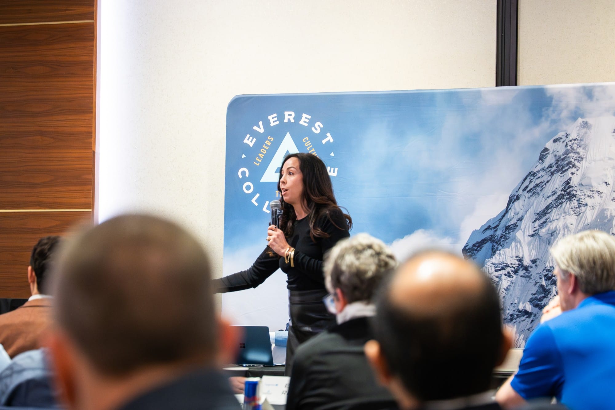 Brittany Tipton speaking to a room of leaders in front of the Everest mountain banner