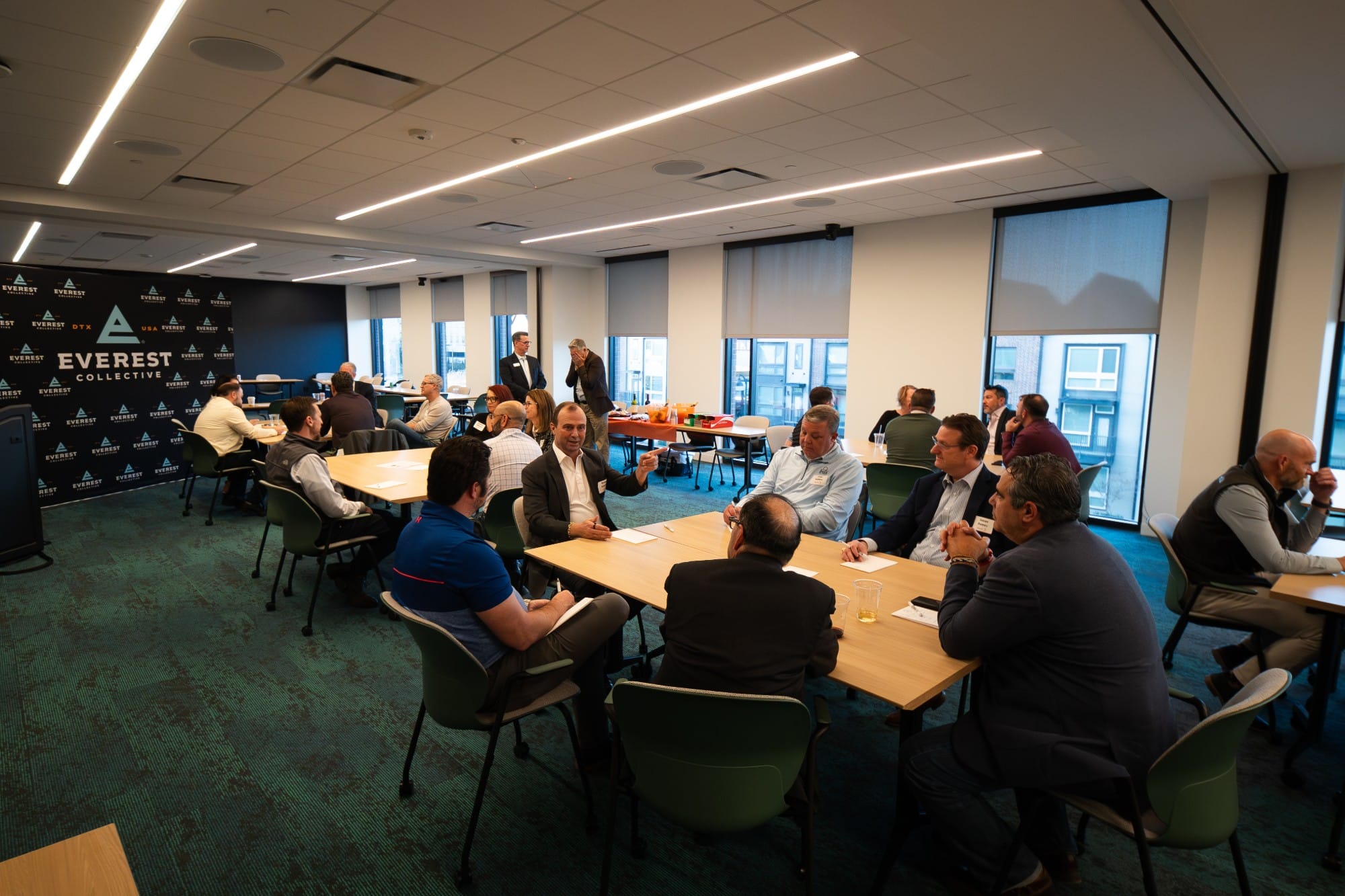 Executives in small-group conversations around tables at a Collective roundtable