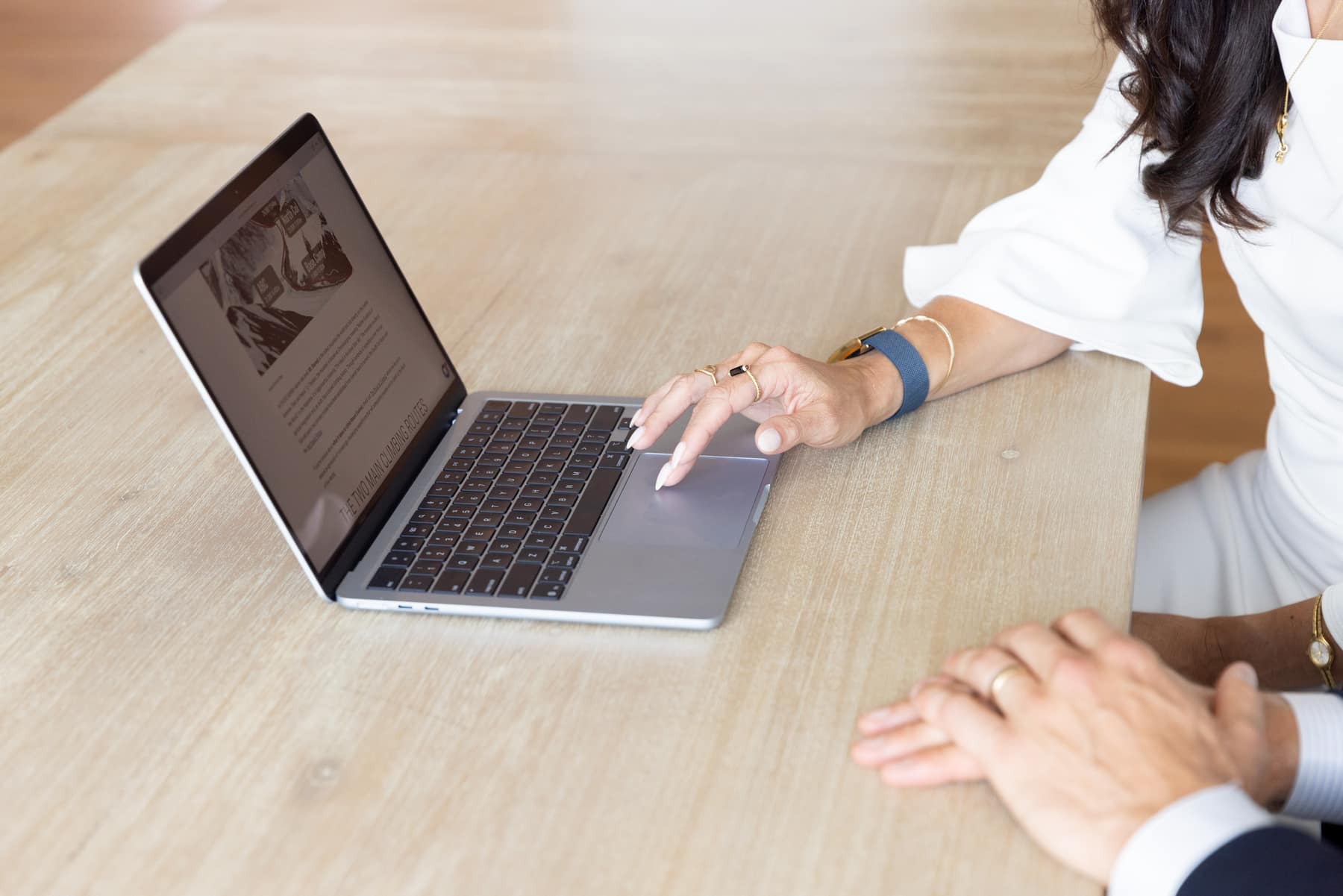 Two leaders at a shared table, one working on a laptop