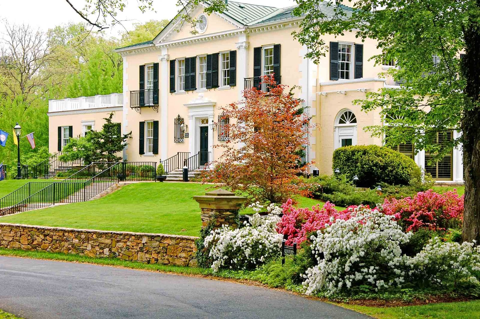 Historic white Airlie House with spring flower beds