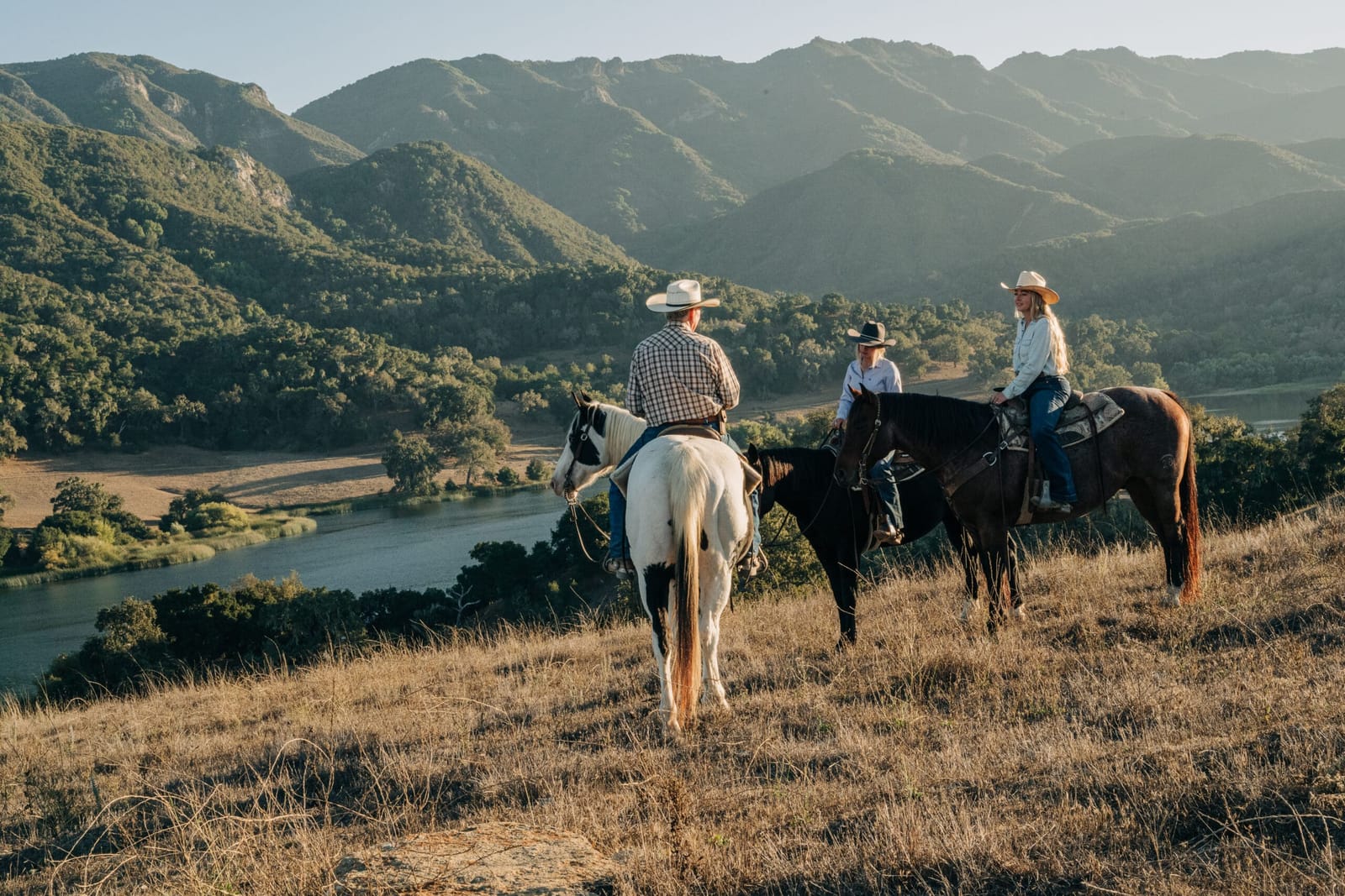 Horseback riders overlooking a lake and green mountains