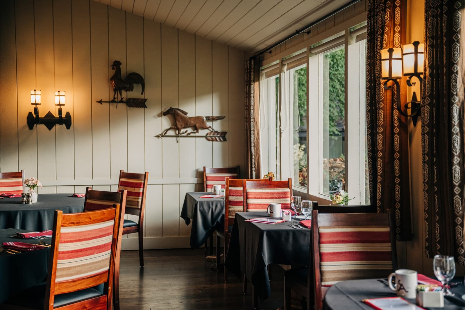 A ranch dining room with wood walls and set tables