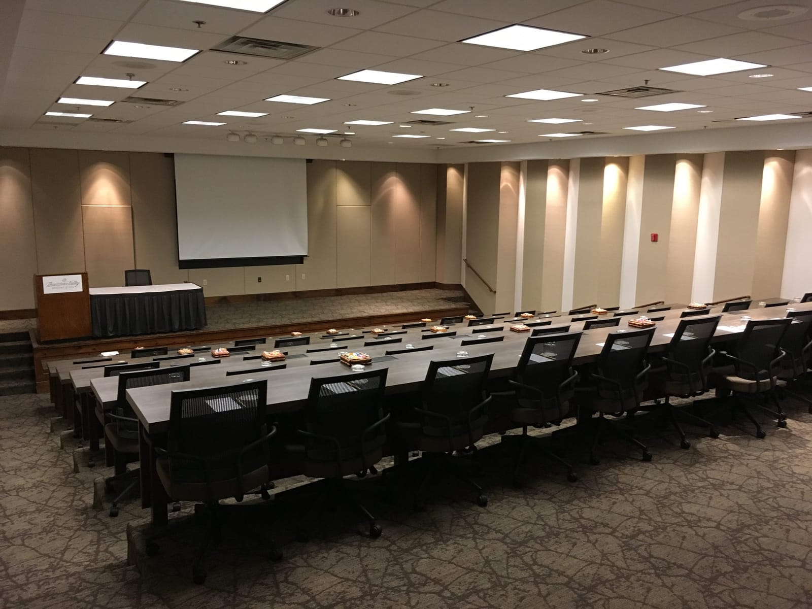 A conference room with rows of tables facing a projection screen