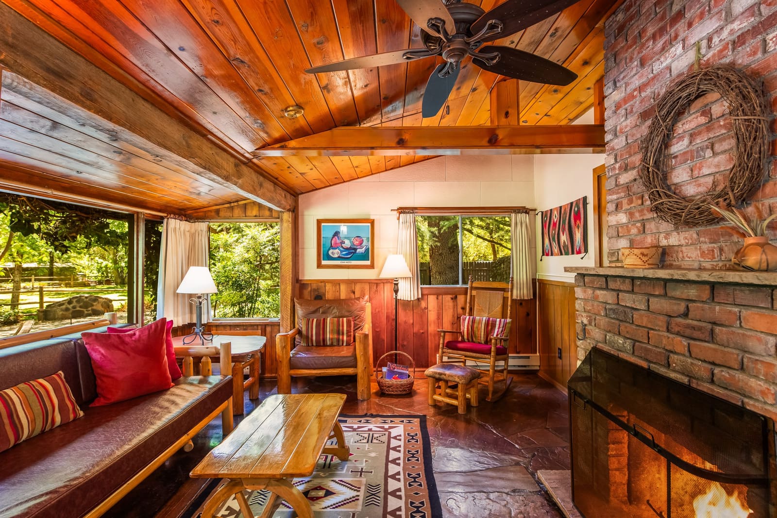 Cabin living room with wood ceiling, brick fireplace and Southwest rugs