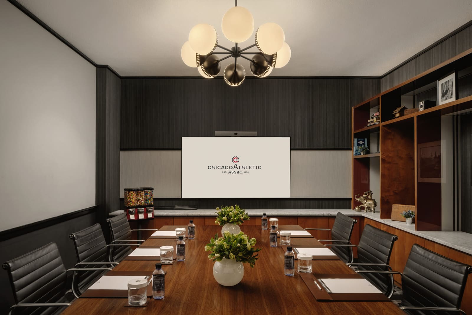 Boardroom with a long walnut table and a video screen