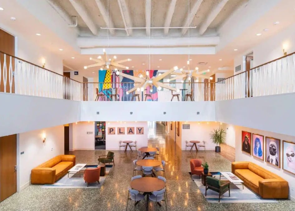 A two-story atrium with lounge seating, round tables and a balcony above