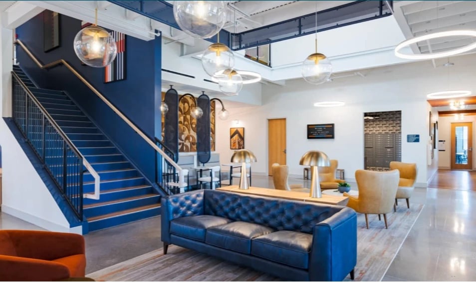 A lounge with a blue leather sofa, armchairs and a blue staircase