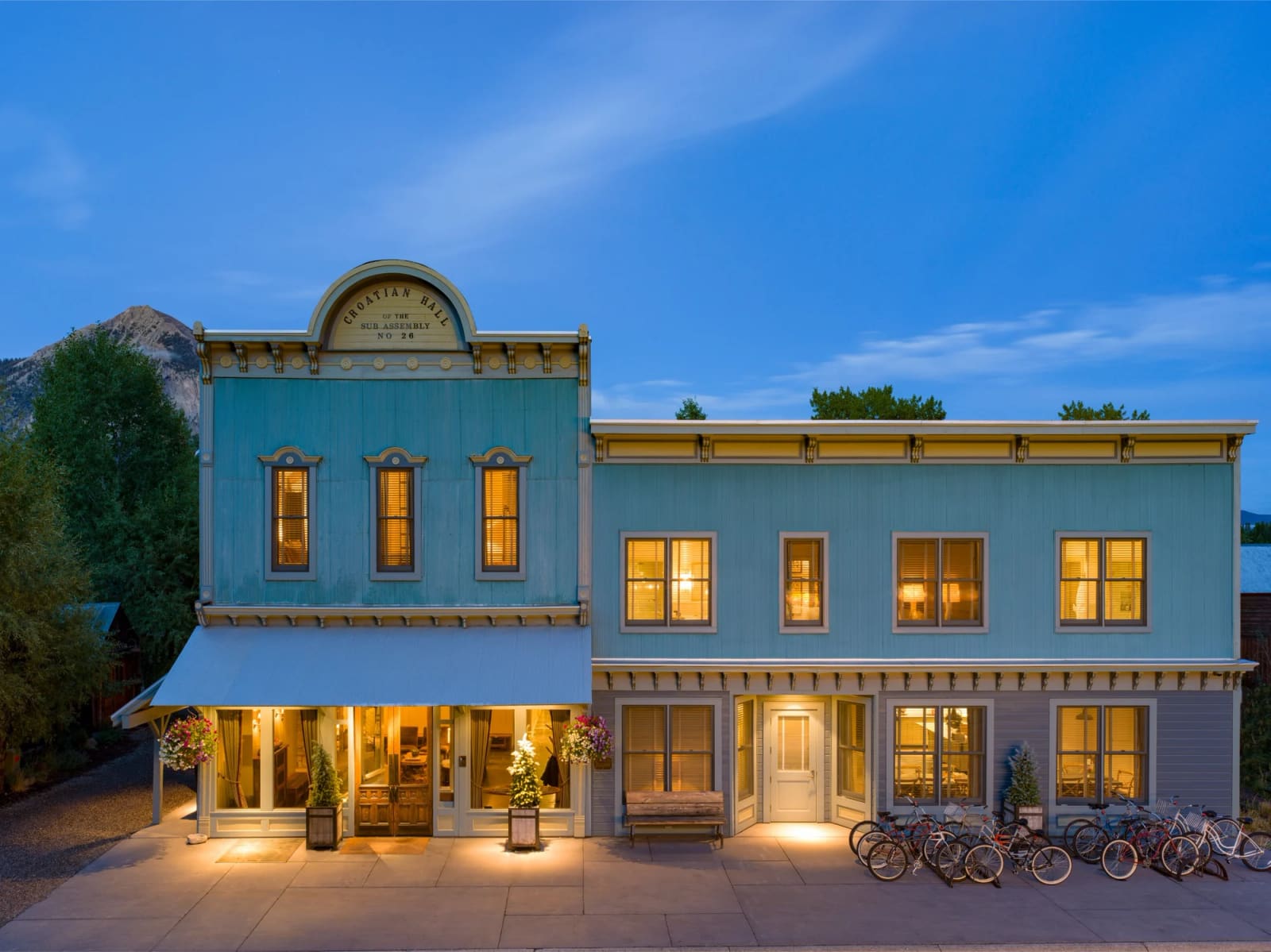 Blue historic facade of Scarp Ridge Lodge at dusk with a mountain behind