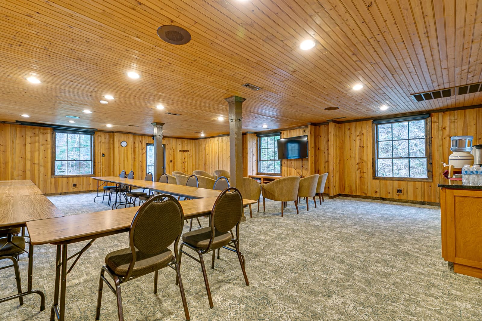 Pine-paneled conference room with tables and lounge chairs