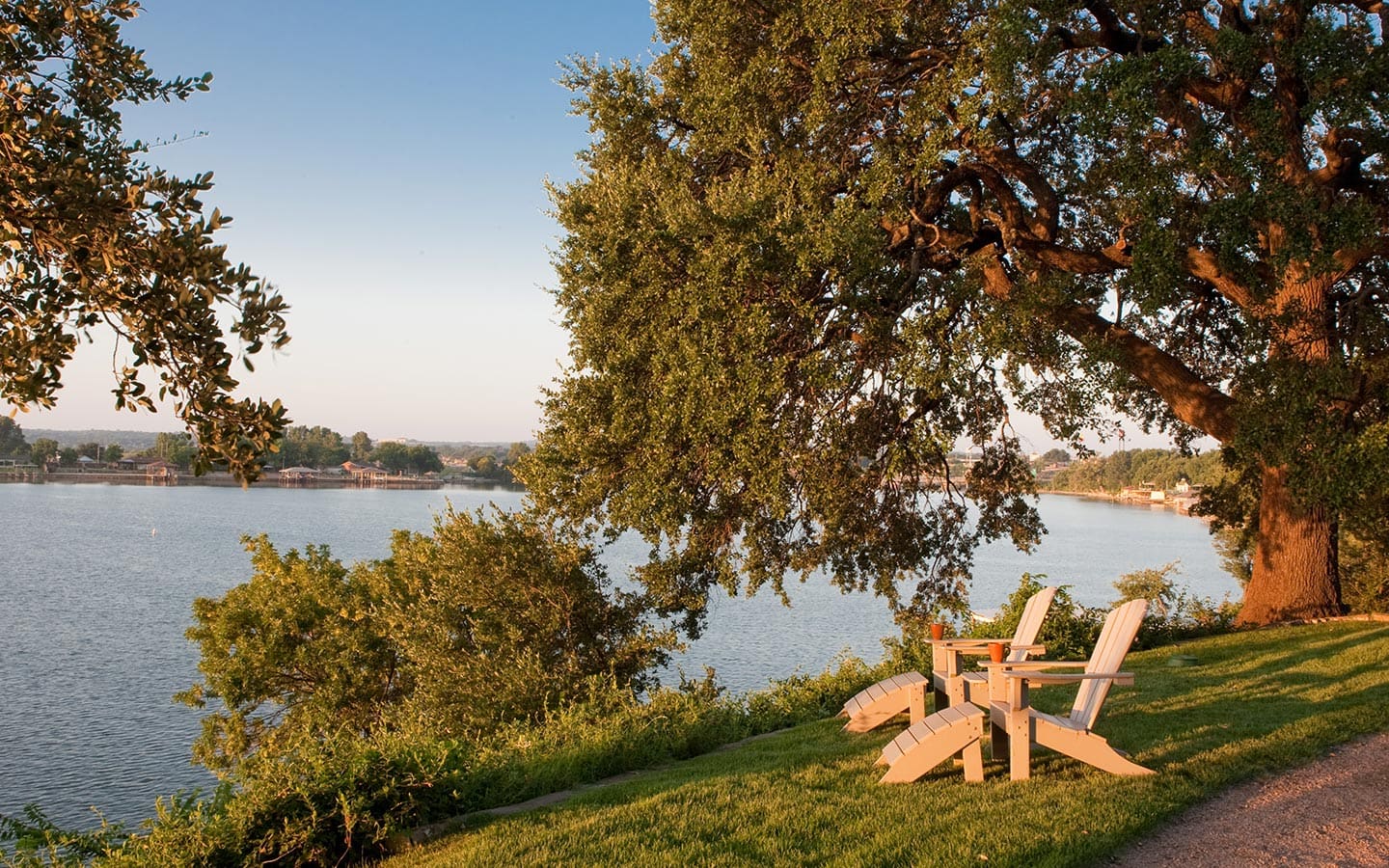 Adirondack chairs under a live oak on the lawn above Lake Granbury