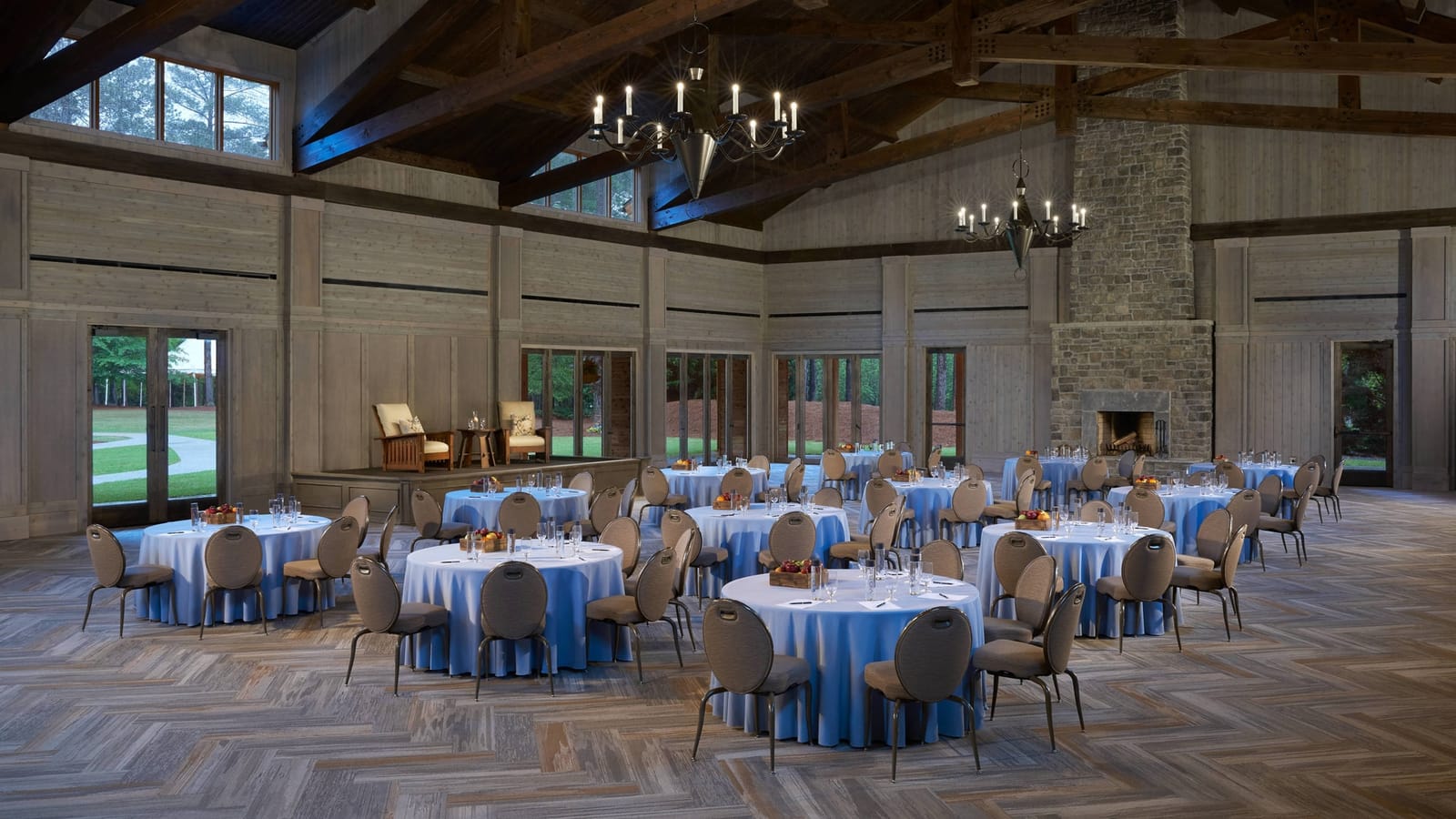 A timber-beamed pavilion with round tables set for an event