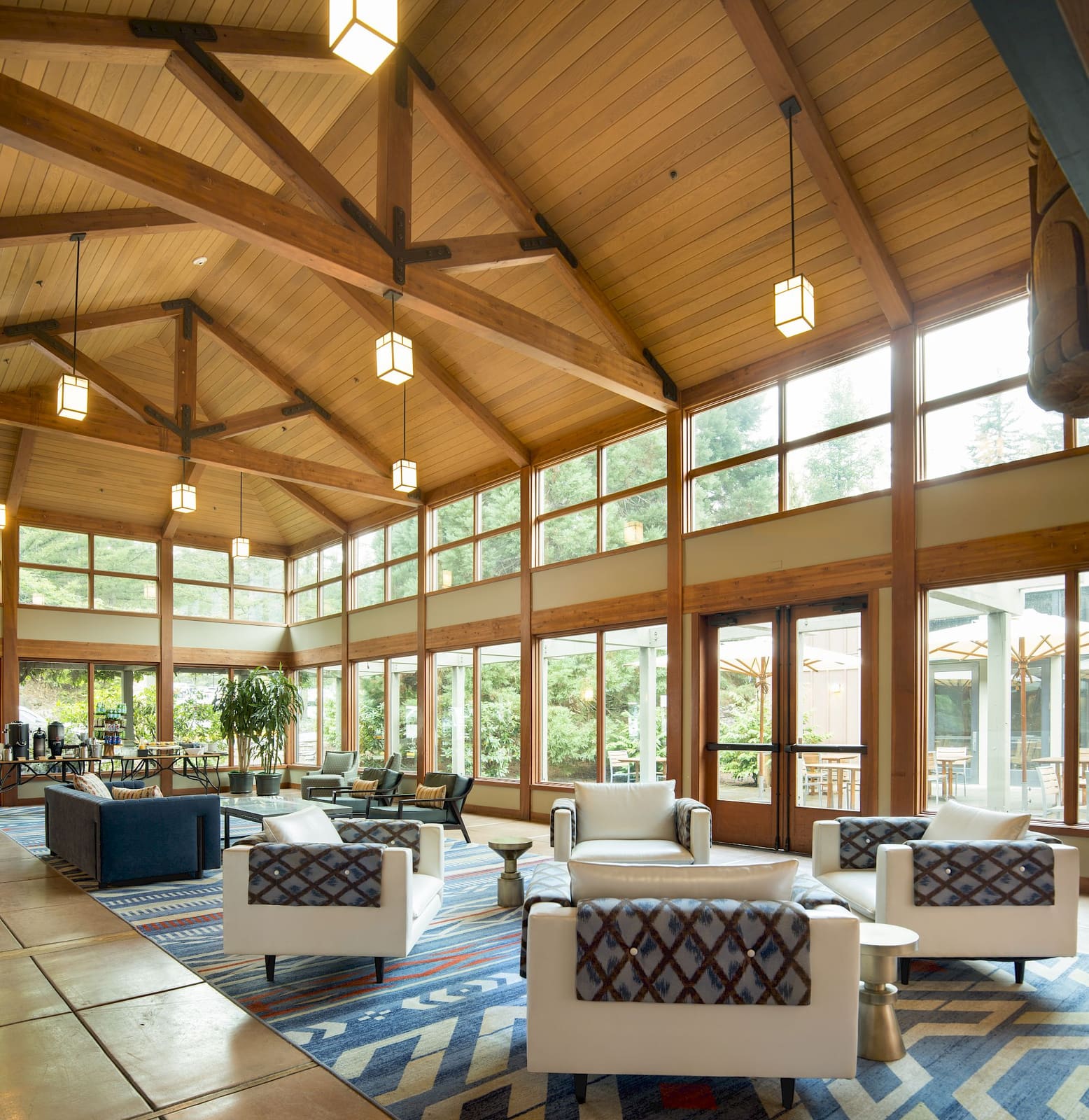 Timber-framed meeting lounge with tall windows onto the forest