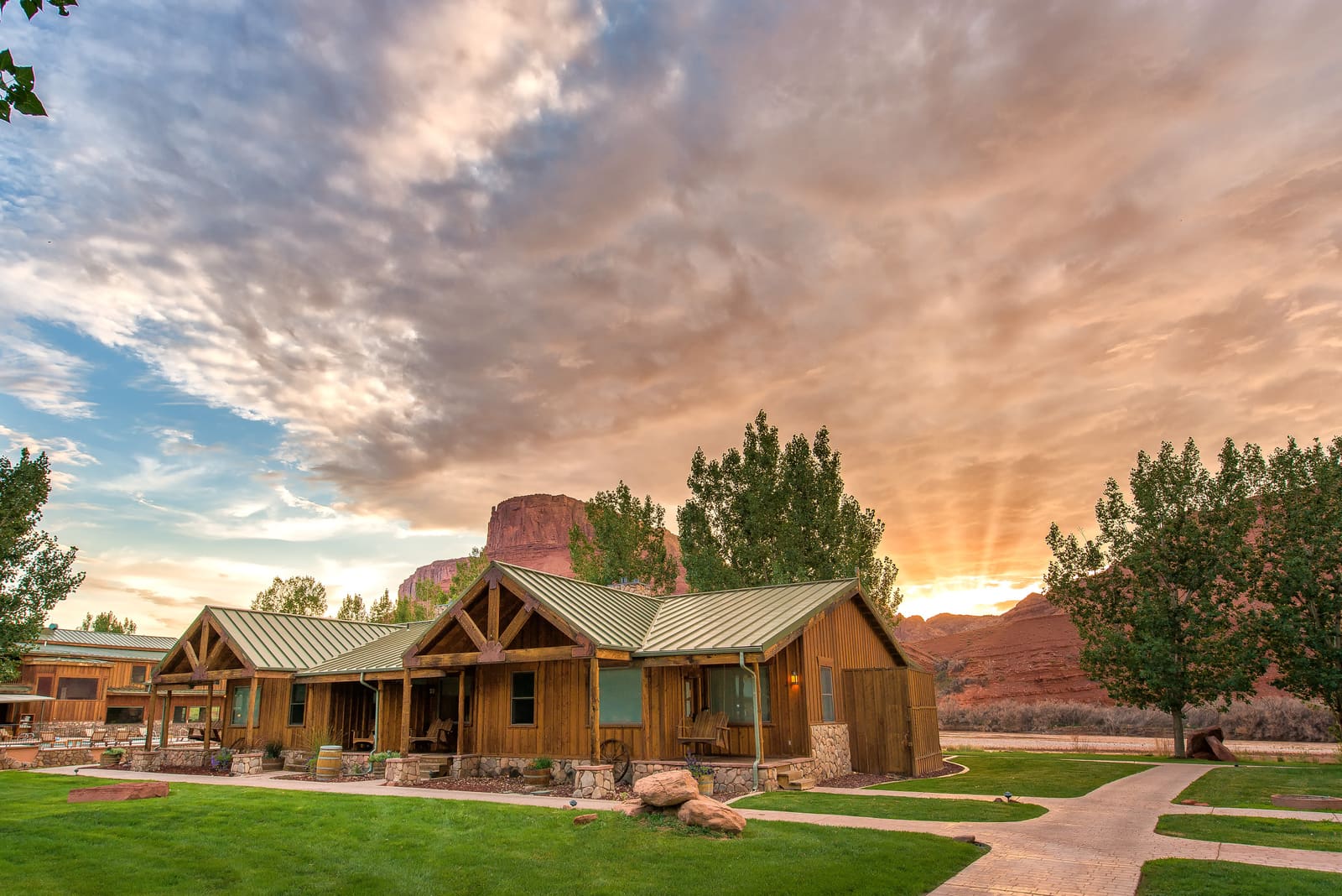 Timber lodge buildings at sunset with a red rock butte behind