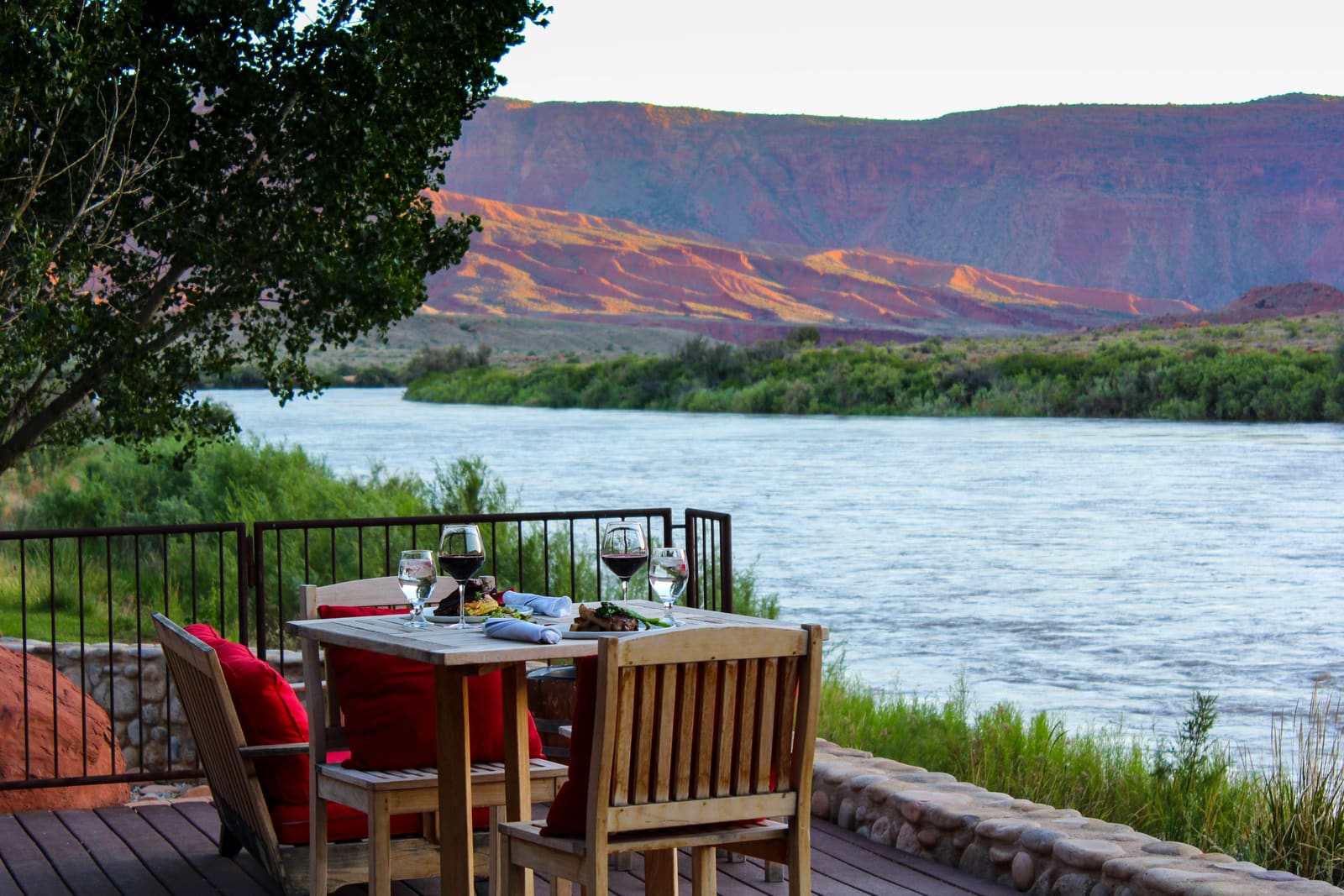 Deck table above the Colorado River facing red mesas at dusk