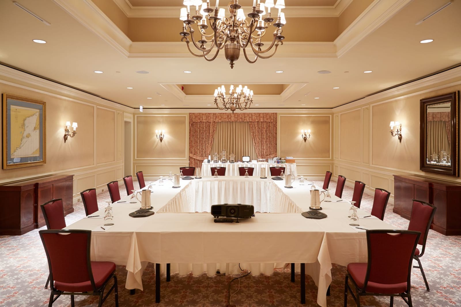 A conference room with a U-shaped table under crystal chandeliers