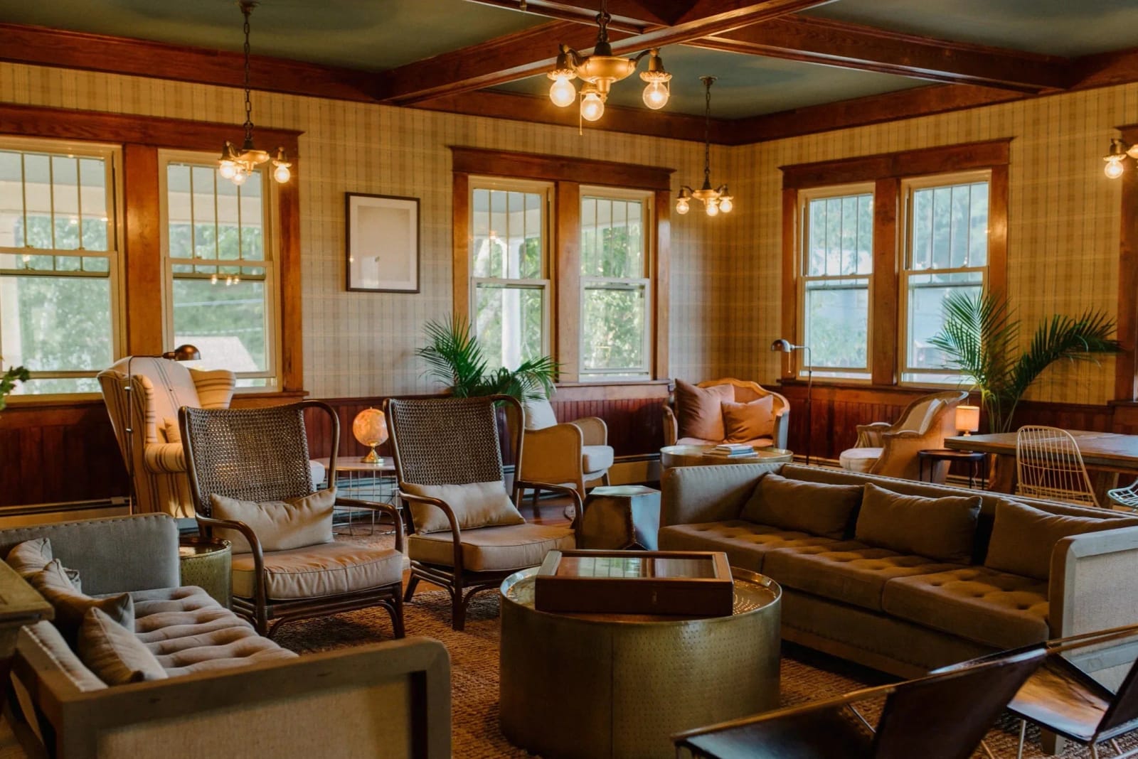 A wood-paneled great room with sofas, armchairs and tall windows