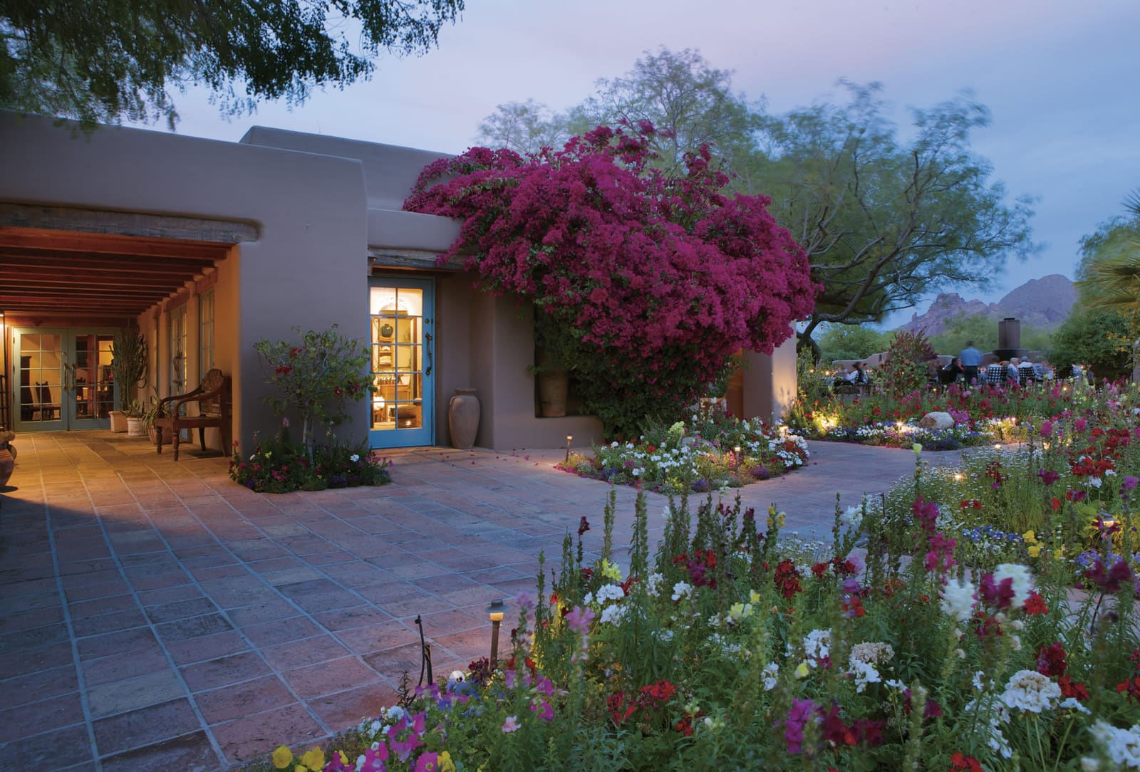 Adobe inn entrance with bougainvillea and flower gardens, Camelback Mountain at dusk