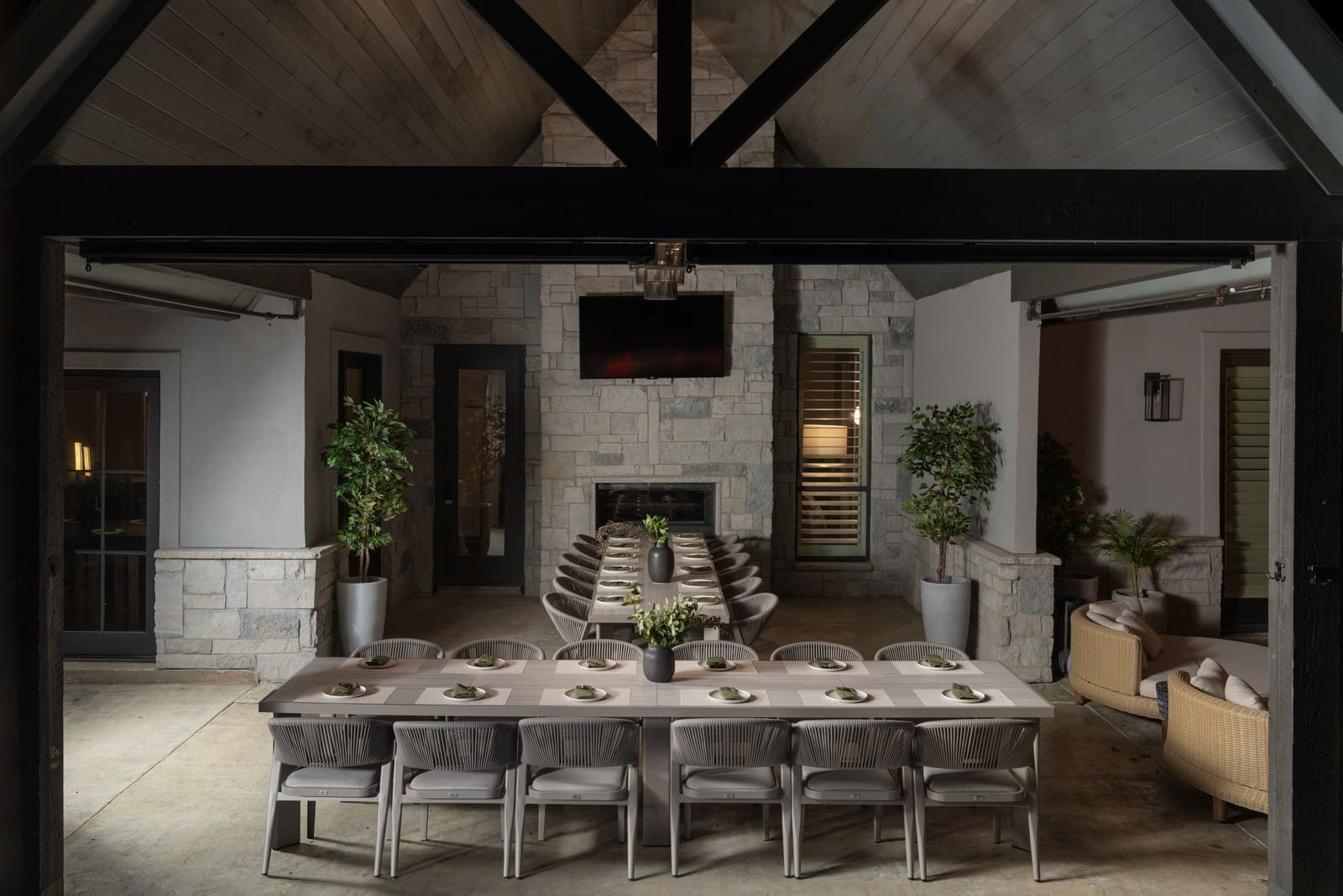 Covered outdoor dining pavilion with a long table and stone fireplace