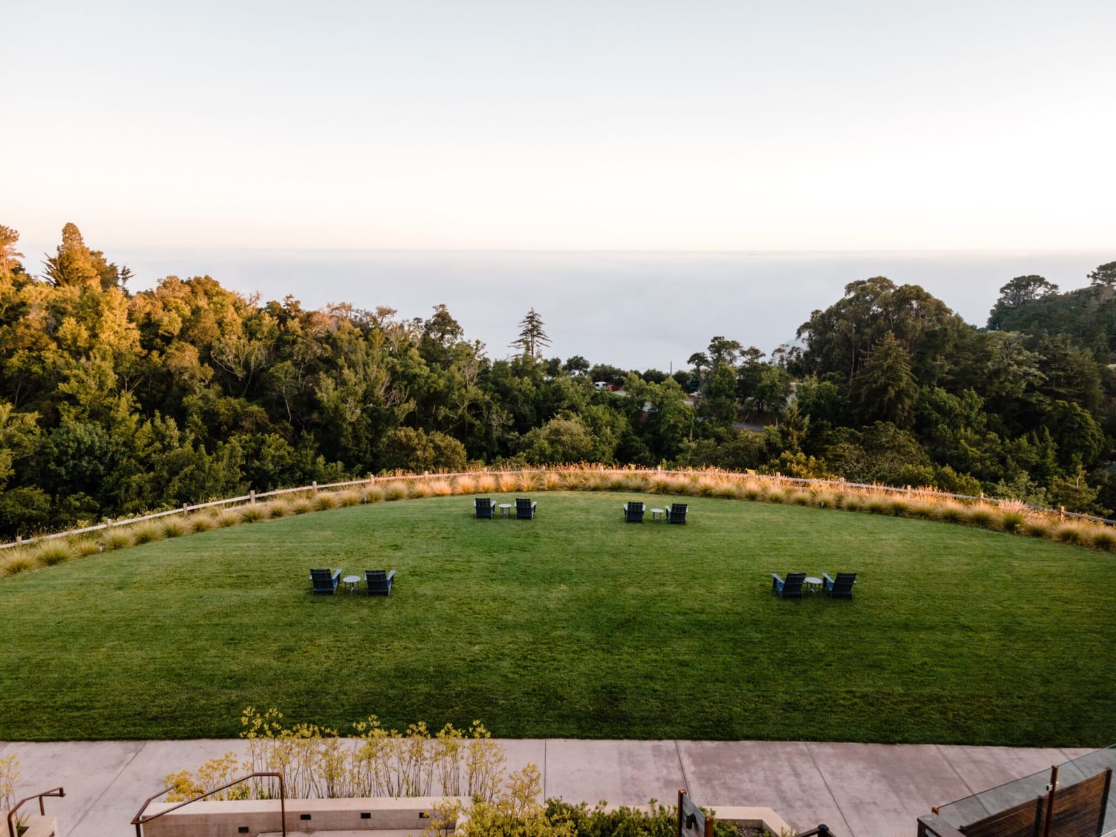 Ocean Meadow Lawn with chairs and the Pacific Ocean beyond the trees