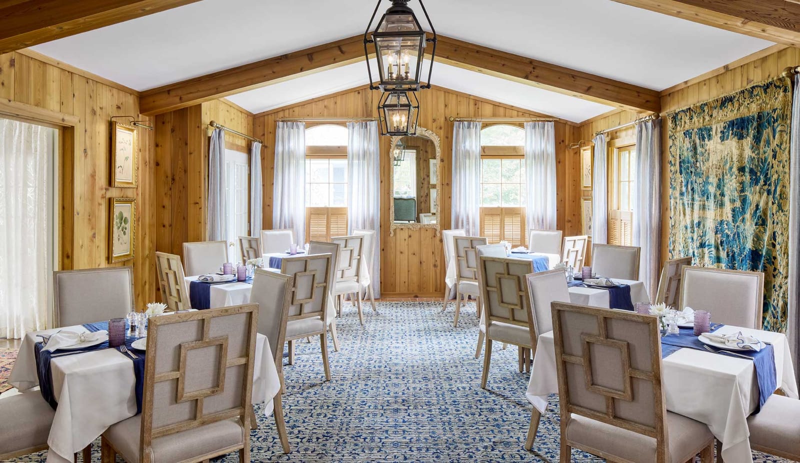 A garden dining room with a lantern and tables set for a group
